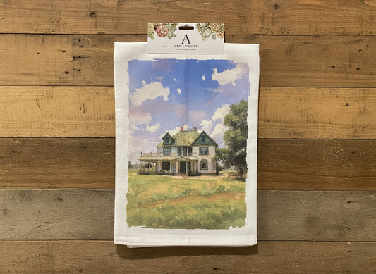 Towel with a printed design of a house and sky hanging on a wall.