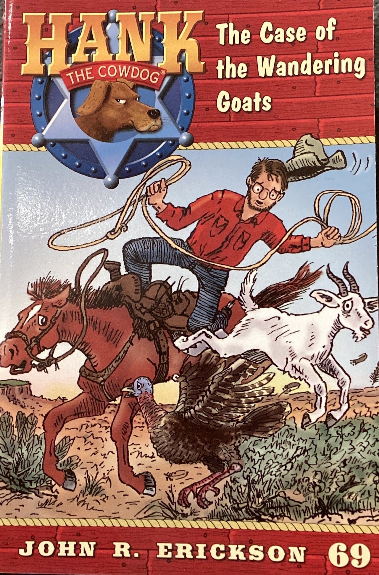 Book titled 'Hank the Cowdog: The Case of the Wandering Goats' by John R. Erickson on a dark surface.