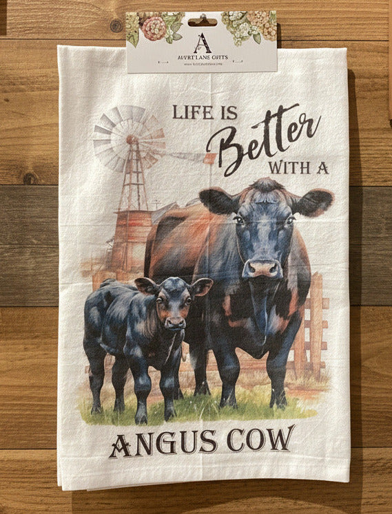 Tea towel with cow illustration and text on a wooden wall background