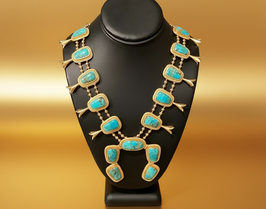 Gold necklace with turquoise stones on a black stand against a blurred background