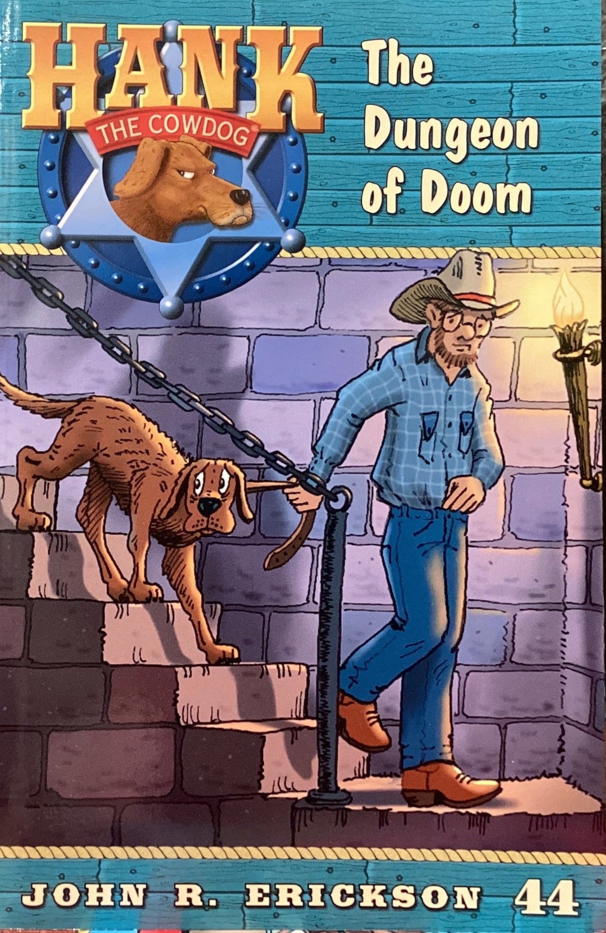 Book titled 'Hank the Cowdog: The Dungeon of Doom' by John R. Erickson on a gray surface.