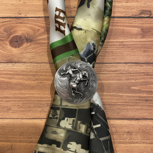Silver belt buckle with a detailed design on a camouflage-patterned belt against a beige background