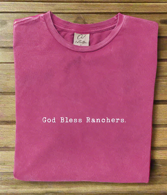 Folded pink t-shirt with 'God Bless Ranchers' text on a white background