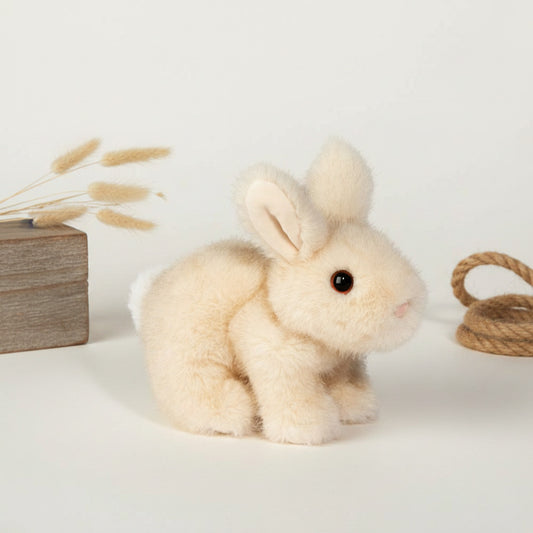 A small plush rabbit toy in cream-colored faux fur with a black bead eye and pink nose, shown against a plain white background.