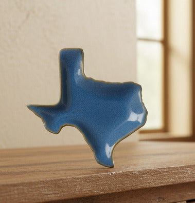 Blue ceramic dish shaped like the state of Texas on a white background