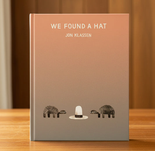 A minimalist art print titled 'WE FOUND A HAT' by Jon Klassen, featuring a peach-to-gray gradient background with a white cowboy hat centered near the bottom, flanked by two small dark patterned animals.