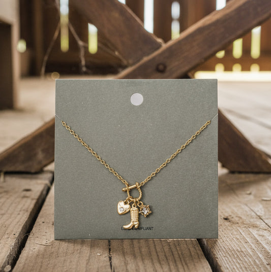 Gold necklace with cowboy boot and star charm on a gray card